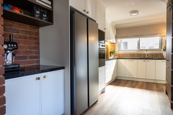 Kitchen Renovation in a u shape design with hampton style parchment cabinetry and black appliances with matching benchtops topped with brass handles