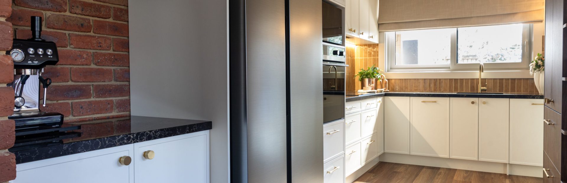 Kitchen Renovation in a u shape design with hampton style parchment cabinetry and black appliances with matching benchtops topped with brass handles