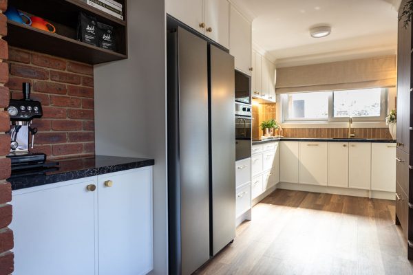 U shaped kitchen featuring parchment Hampton style cabinetry matched with Sepia Walnut overhead and pantry with black benchtops