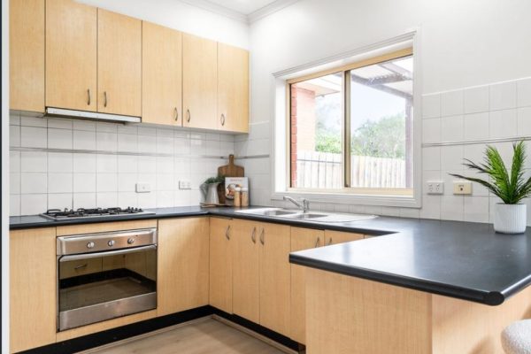 Light timber and black benchtops in u shape before kitchen renovation