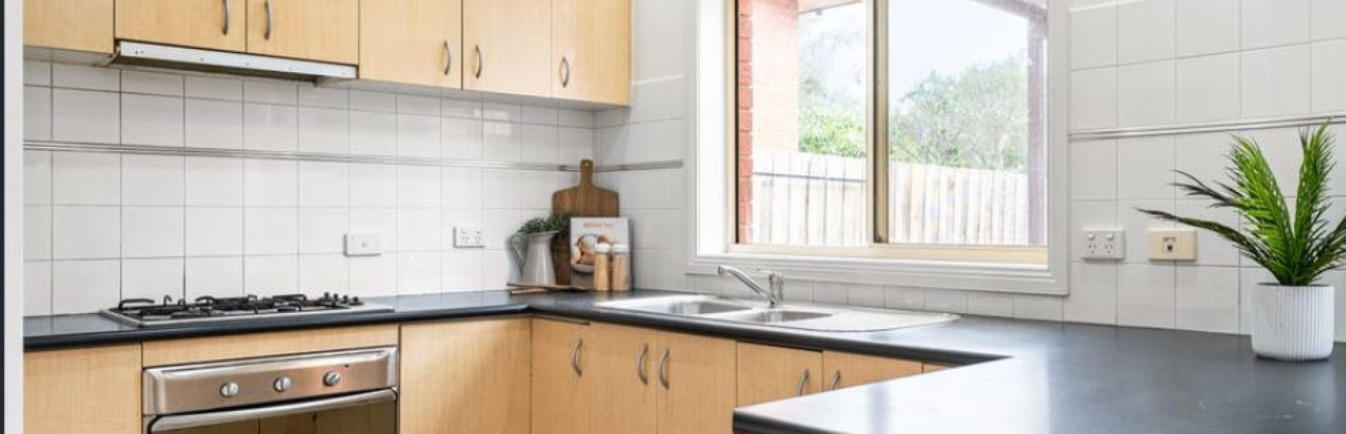 Light timber and black benchtops in u shape before kitchen renovation