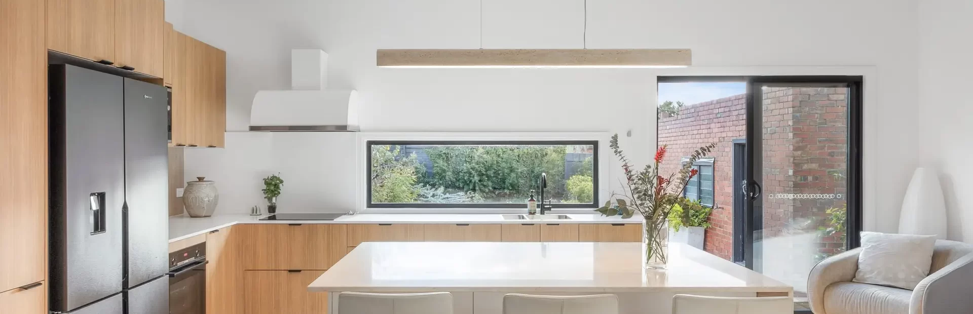 Oak timber laminate and white kitchen cabinetry with a standalone island bench in a u shaped kitchen