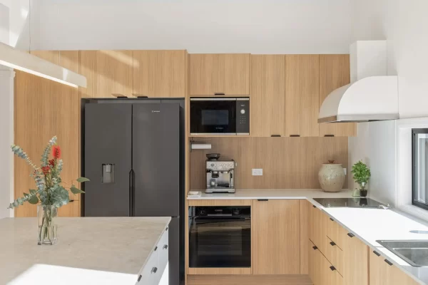 Oak Timber look kitchen cabinetry in us hspaed kitchen with black oven, microwave and fridge