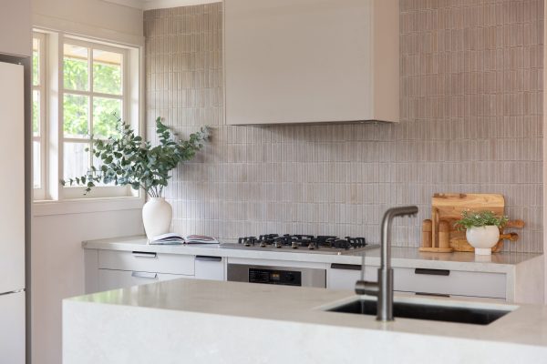 Galley style kitchen using oyster grey cabinet drawers and large standalone island bench featuring sink and tap