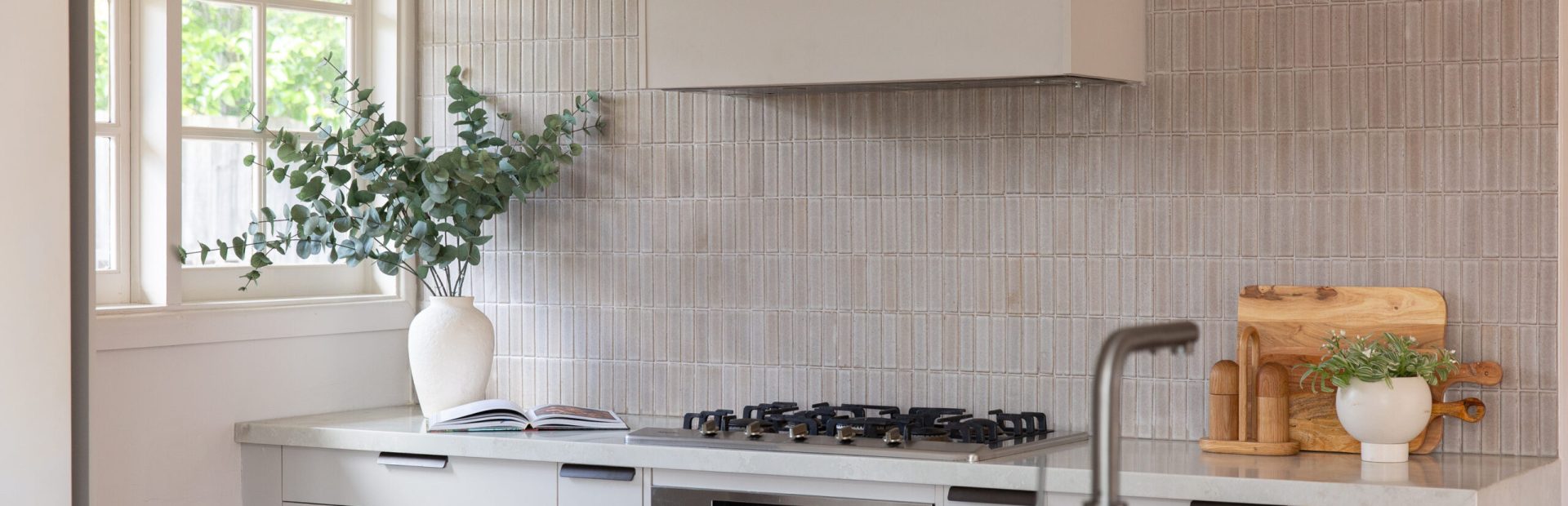 Galley style kitchen using oyster grey cabinet drawers and large standalone island bench featuring sink and tap