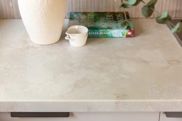 Marbled style stone benchtop called Jade Sky with vase, receipe book and three small white containers