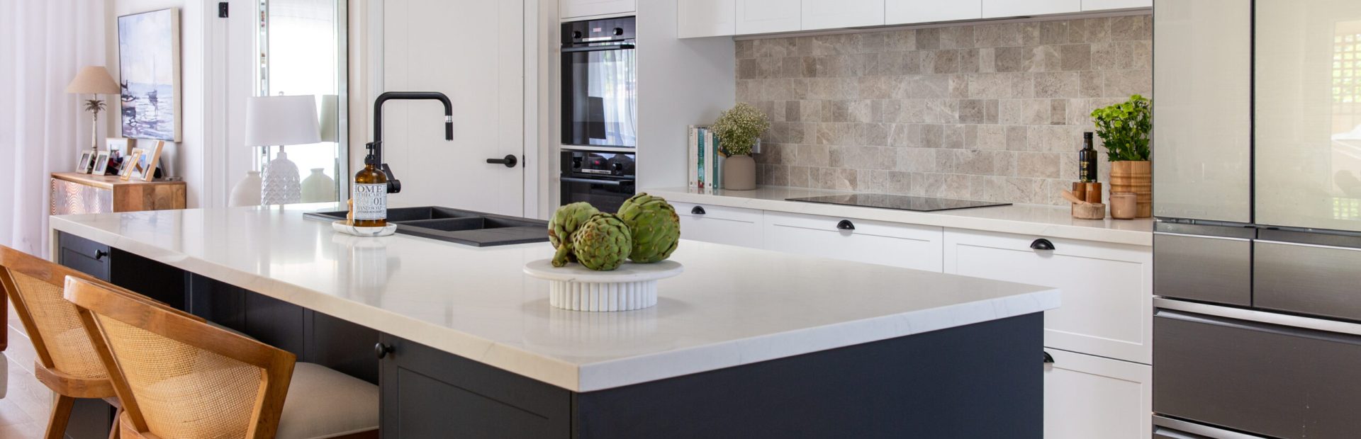 White and dark grey galley style kitchen with grey tiled splashback and large island bench