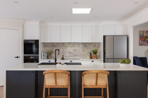 Galley style shaker kitchen featuring white and dark grey cabinetry with black wall oven tower and stainless steel fridge