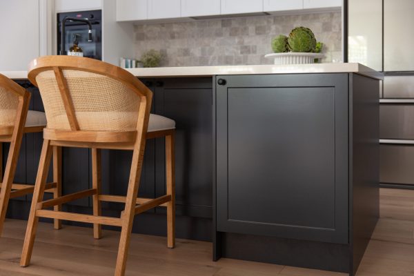 Kitchen island bench featuring dark grey shaker style cabinetry and white stone benchtops