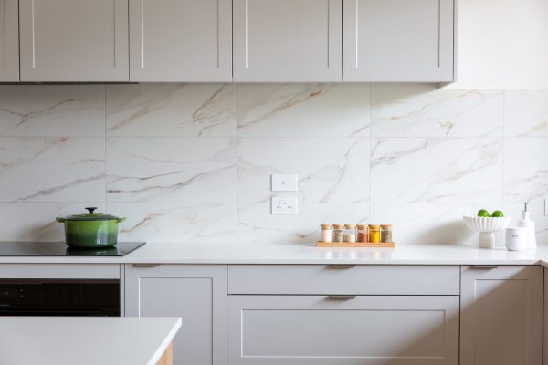 Light grey kitchen cabinetry in a u shaped kitchen displaying handleless and chrome handles with doors and drawers