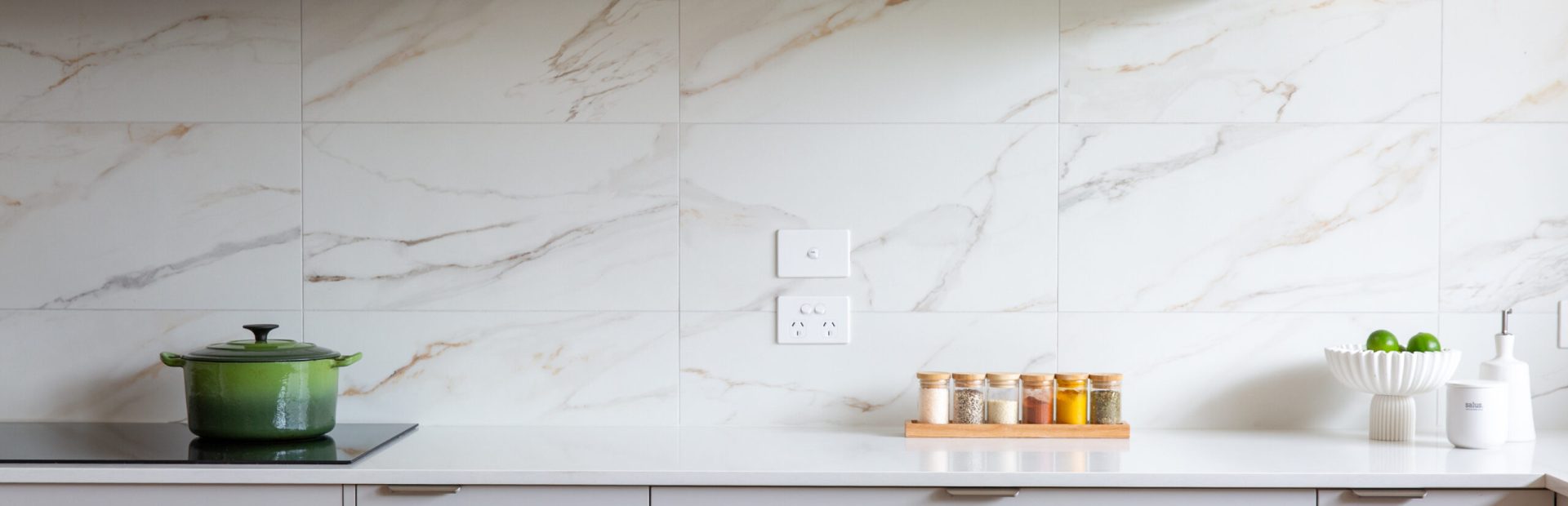 Light grey kitchen cabinetry in a u shaped kitchen displaying handleless and chrome handles with doors and drawers