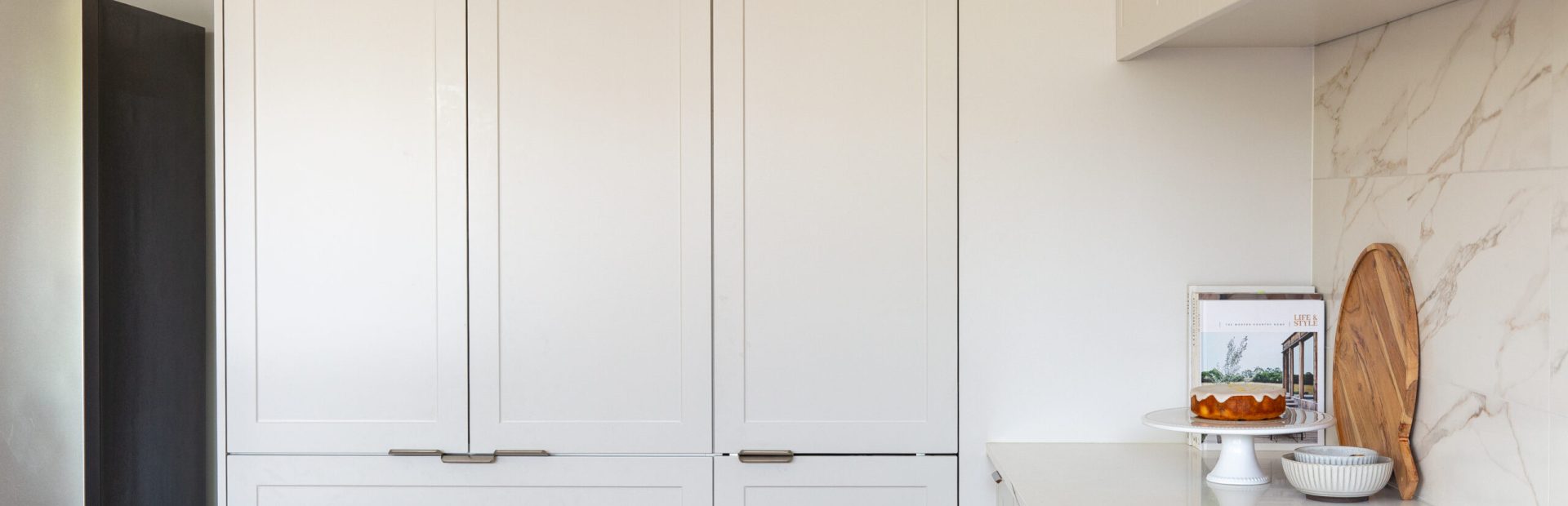 Light grey kitchen cabinetry doors featuring a pantry with pot drawers below