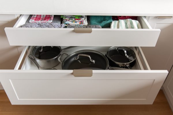 Deep kitchen cabinetry drawers in light grey with chrome handles displaying pots and pans