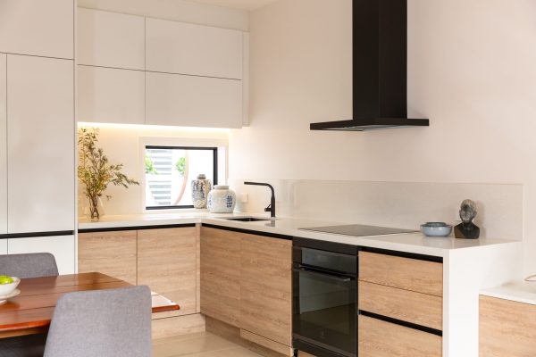 u shaped kitchen with timber laminate cabinetry and white benchtops with black rangehood and black oven