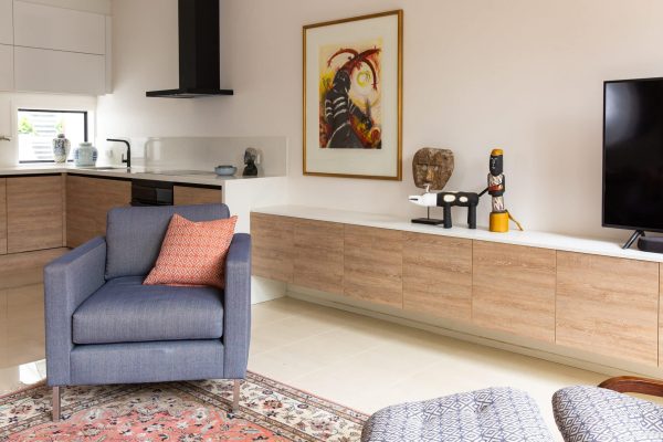 Living room cabinetry in oak timber flows into the kitchen with white benchtops