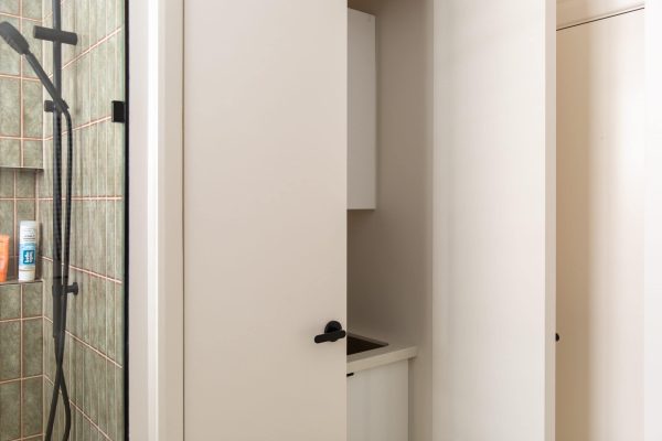 Laundry with sink hidden behind white doors