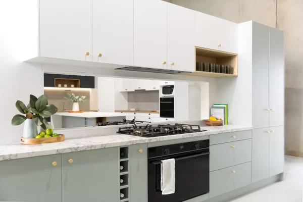 galley kitchen with green cabinetry and white overhead cabinetry with open shelf in timber style