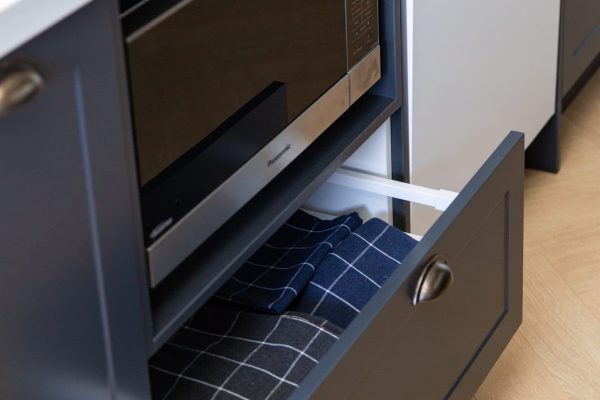 Pull out pot drawer cabinet underneath microwave unit next to dishwasher