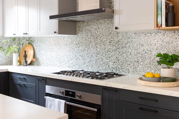 Kitchen cabinetry with terrazzo feature tiled splashback and standalone ducted rangehood