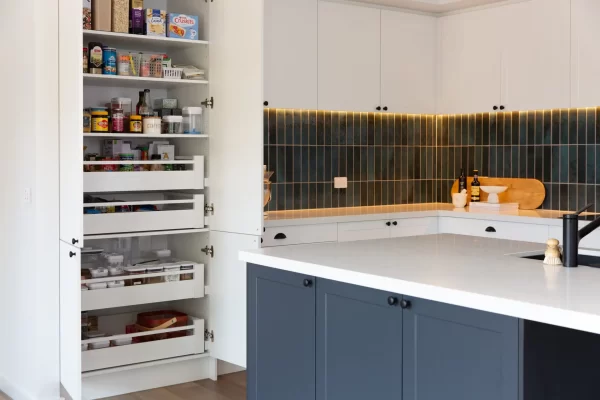 Kitchen pantry with pull out shelves for easy storage and reach including green tiled splashback