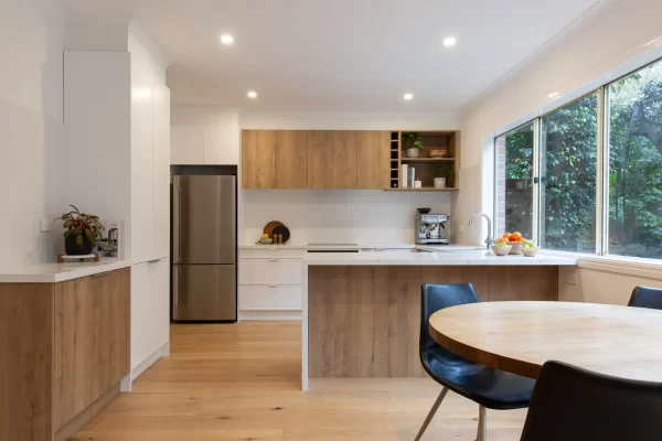 Galley style modern kitchen featuring white and timber cabinetry with coffee machine on bench