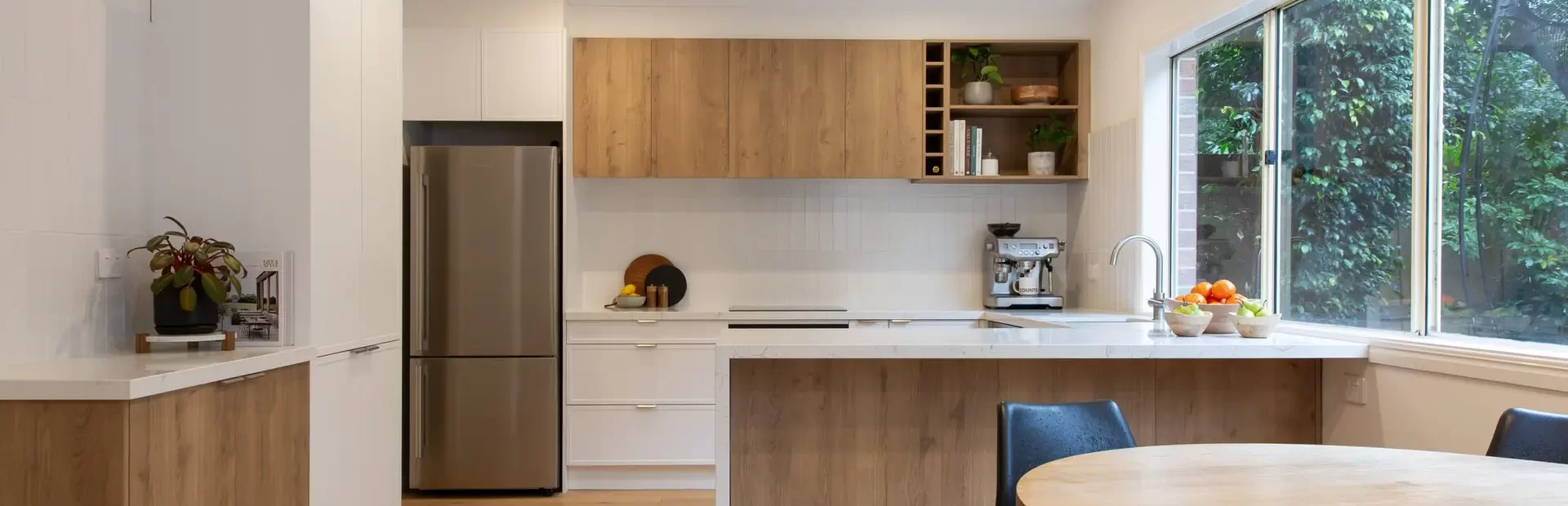 Galley style modern kitchen featuring white and timber cabinetry with coffee machine on bench