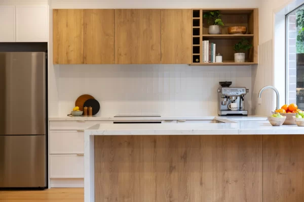 Oak Timber and white hampton style galley kitchen with large island bench, open shelf displaying books and pot plants