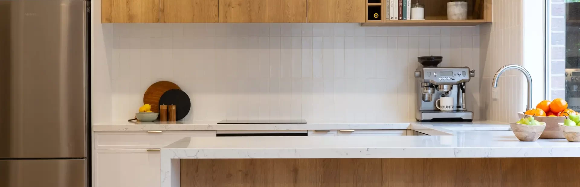Oak Timber and white hampton style galley kitchen with large island bench, open shelf displaying books and pot plants