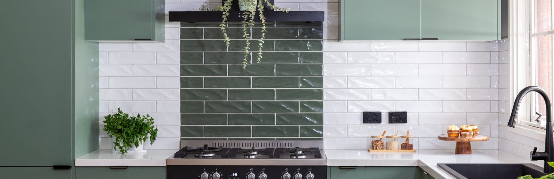 U shaped kitchen featuring sage green cabinetry with white stone benchtops and white and green tiled splashback