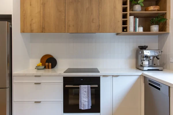 white hampton style kitchen cabinetry with overhead timber oak coloured cabinetry with wine rack and pot plants on display