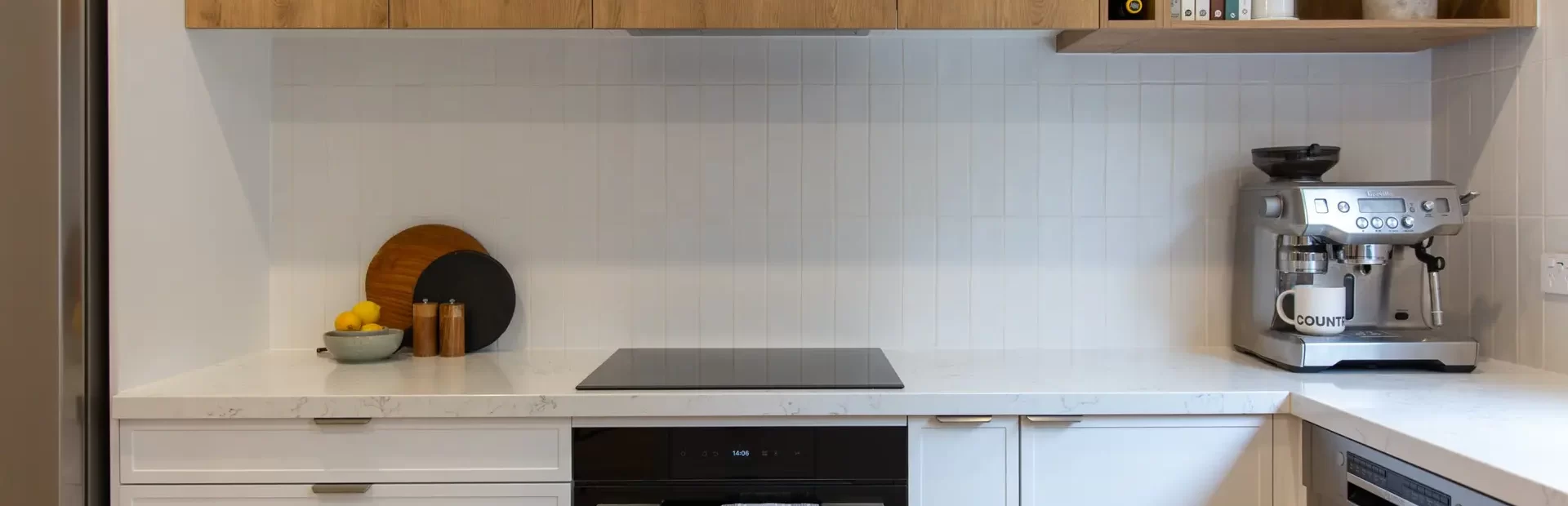 white hampton style kitchen cabinetry with overhead timber oak coloured cabinetry with wine rack and pot plants on display