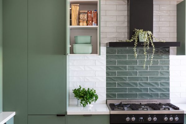 Dark green cabinetry featuring pantry and white and green subway tiles