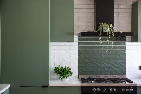 Green kitchen cabinetry featuring pantry and overhead cabinetry with white stone benchtops