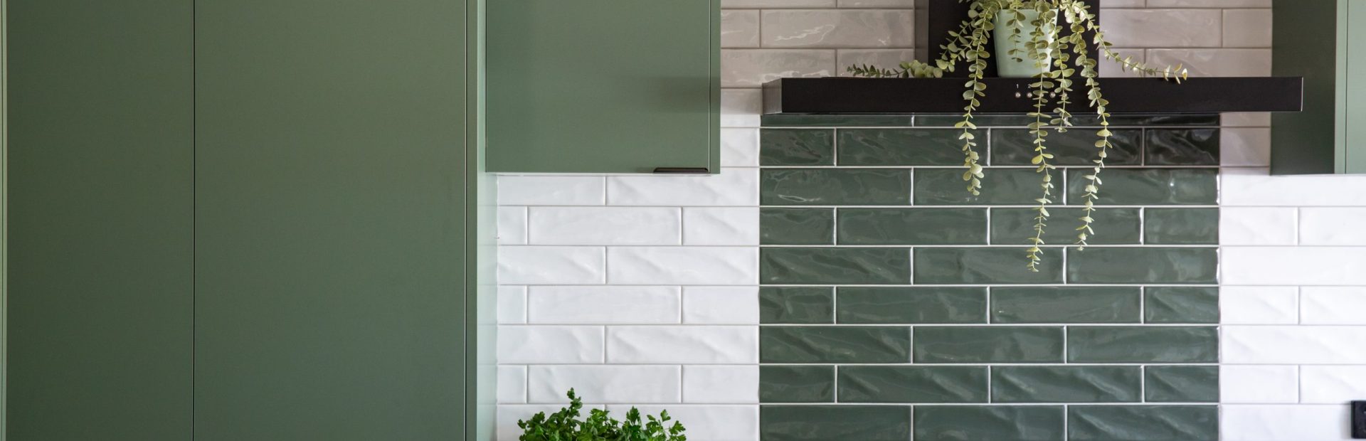 Green kitchen cabinetry featuring pantry and overhead cabinetry with white stone benchtops