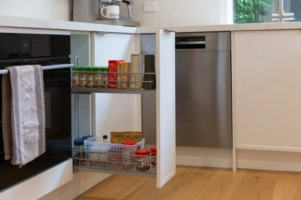 Extra large pull out kitchen spice rack featuring spices and sauces in a white kitchen