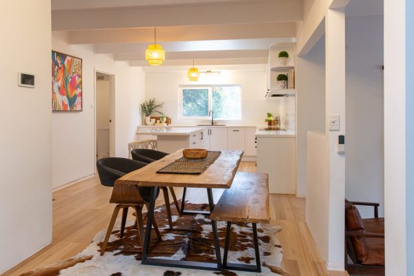 White shaker style kitchen in u shape with timber dining table and timber flooring
