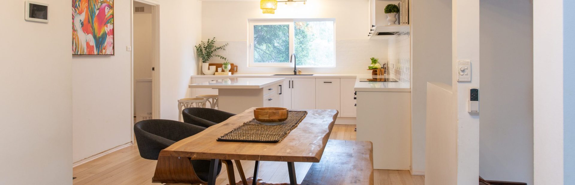 White shaker style kitchen in u shape with timber dining table and timber flooring