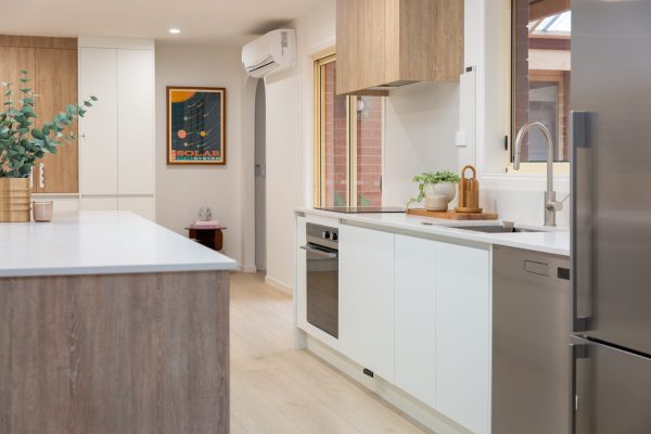 White and oak timber laminate galley kitchen with oak coloured flooring and stainless steel oven and dishwasher