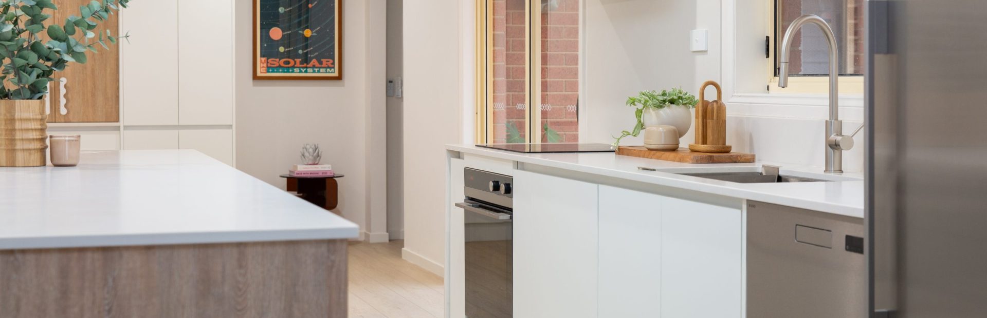 White and oak timber laminate galley kitchen with oak coloured flooring and stainless steel oven and dishwasher
