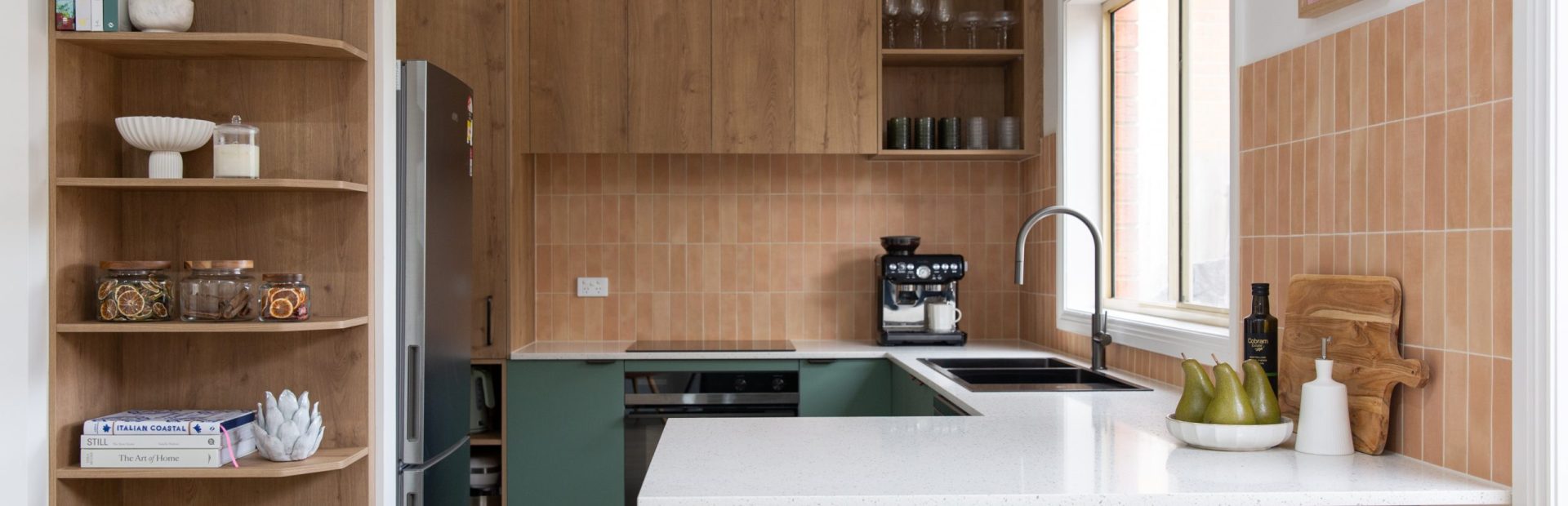 Green cabinetry and oak laminate in u shaped compact kitchen featuring timber bar stools