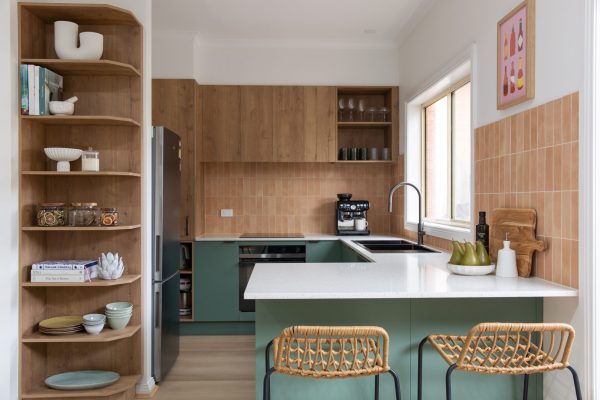 Green cabinetry and oak laminate in u shaped compact kitchen featuring timber bar stools
