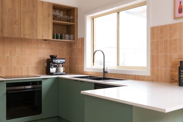 U shaped kitchen featuring green kitchen cabinetry and timber laminate overheads with an open shelf and coffee machine on stone bench