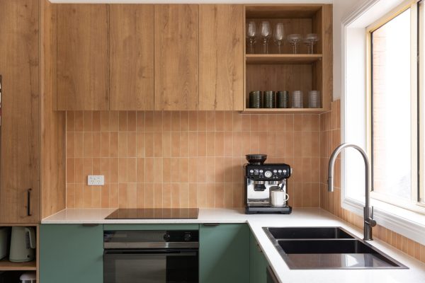 Kitchen featuring timber laminate overhead cabinetry with open shelf displaying glassess and green cabinetry below white stone benchtops