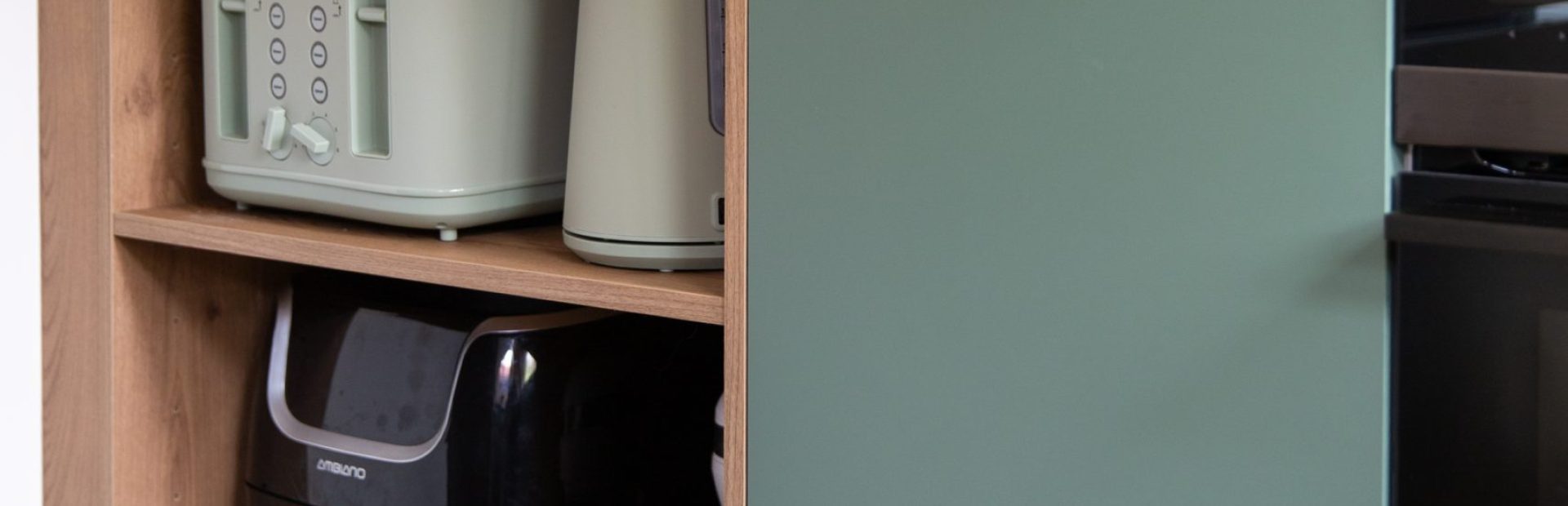 Kitchen open shelfing featuring appliances of toaster, kettle and air fryer housed in green kitchen