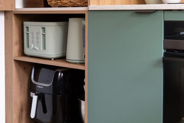 Kitchen open shelfing featuring appliances of toaster, kettle and air fryer housed in green kitchen