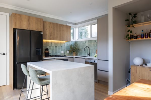 U Shaped kitchen in Yarraville, Melbourne with large standalone stone island bench and cream cabinetry with oak overheads to create warmth