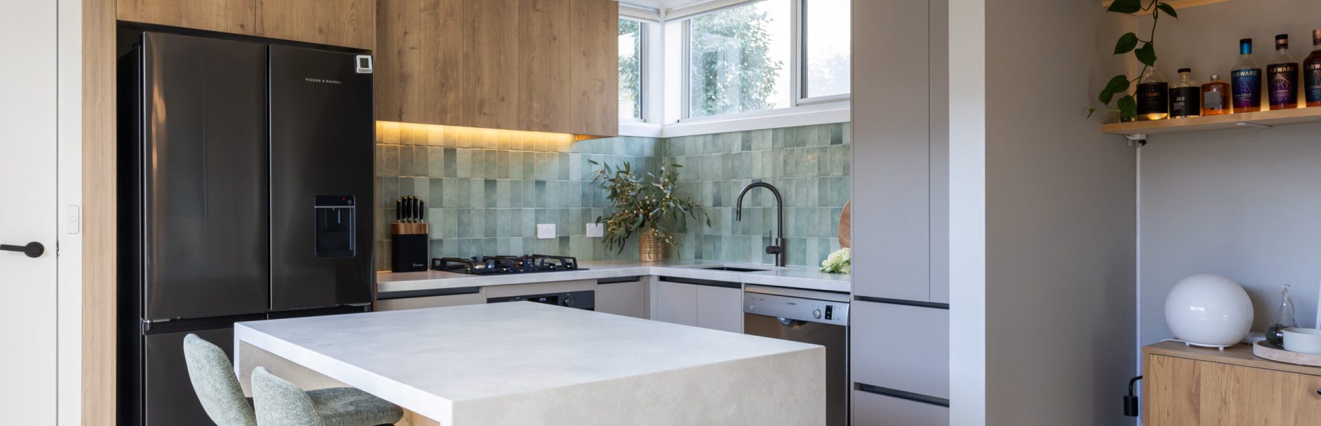 U Shaped kitchen in Yarraville, Melbourne with large standalone stone island bench and cream cabinetry with oak overheads to create warmth