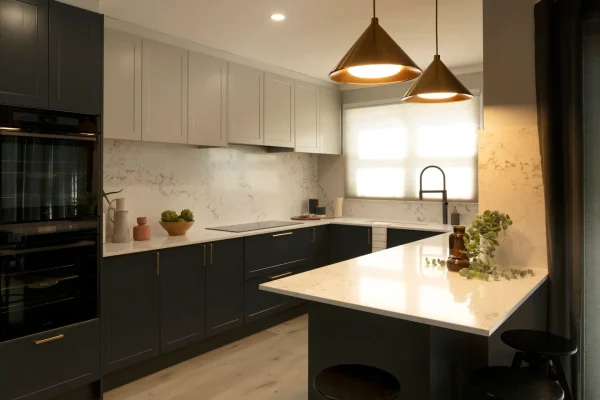 Galley style kitchen featuring shaker cabinetry in terril base and oyster colour overhead cabinetry with pendant lights in brass and white stone benchtops with styling items on bench as featured on Selling Houses Australia in North Fitzroy