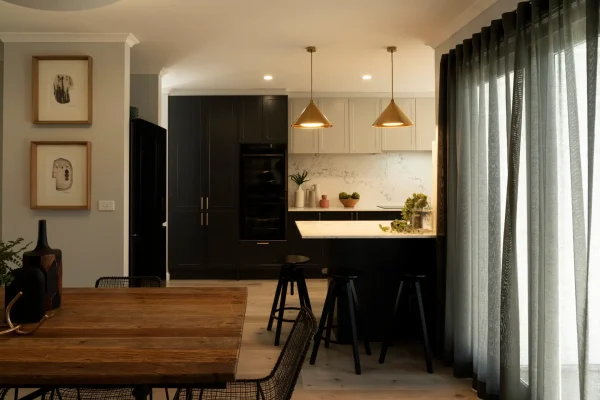 Shaker kitchen in home featuring shaker terril and oyster cabinetry with breakfast bar and three black stools around the breakfast bar with pendant lighting and timber oak flooring as featured in Selling Houses Australia
