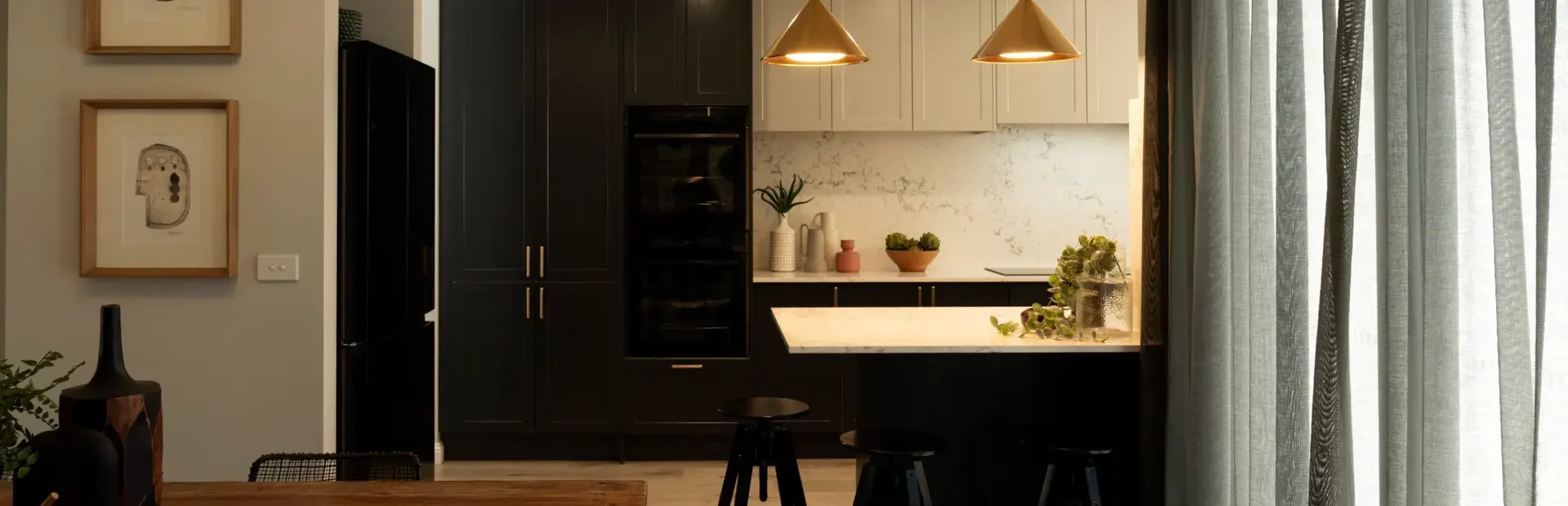 Shaker kitchen in home featuring shaker terril and oyster cabinetry with breakfast bar and three black stools around the breakfast bar with pendant lighting and timber oak flooring as featured in Selling Houses Australia